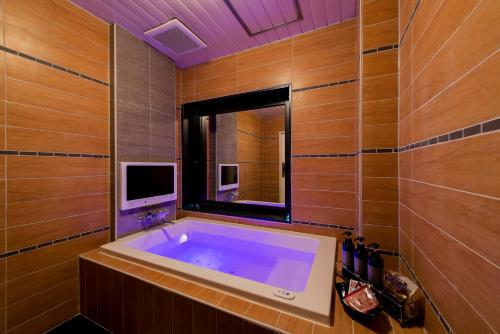 a bathroom with a large tub with a tv in it at Hotel CUE Machida(Adult Only) in Machida