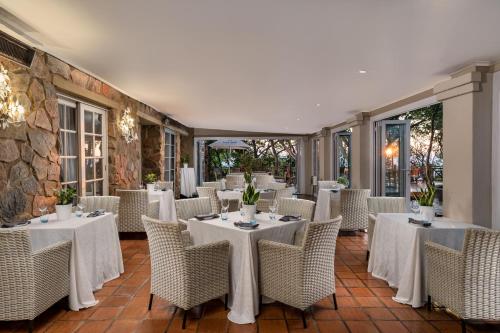 a dining room with white tables and chairs at Mount Grace Hotel & Spa in Magaliesburg