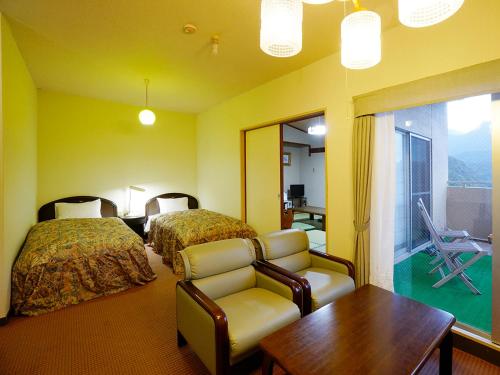 a hotel room with two beds and a chair and a table at Hotel Yakushima Sanso in Yakushima