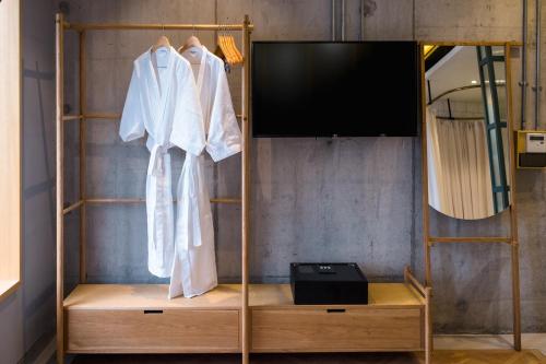 a wardrobe with a television and a white robe at KLoe Hotel in Kuala Lumpur