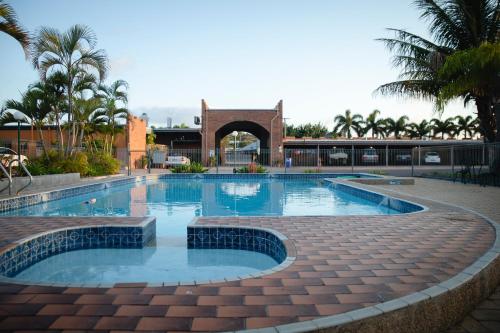 una piscina en un patio con un edificio en Castle Motor Lodge, en Bowen