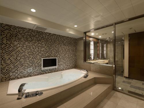 uma grande casa de banho com banheira e uma televisão em Meguroholic Hotel em Tóquio