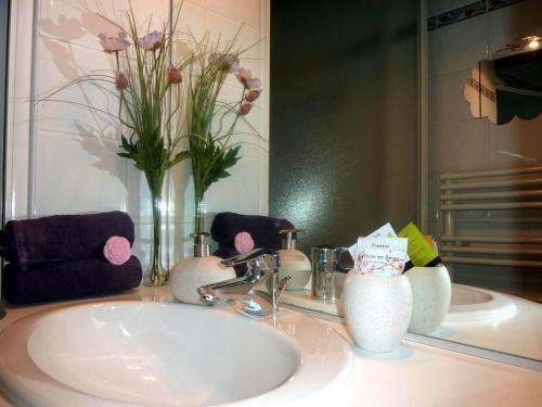 La salle de bains est pourvue d'un lavabo, d'un miroir et de fleurs. dans l'établissement Cannes Plage, à Cannes