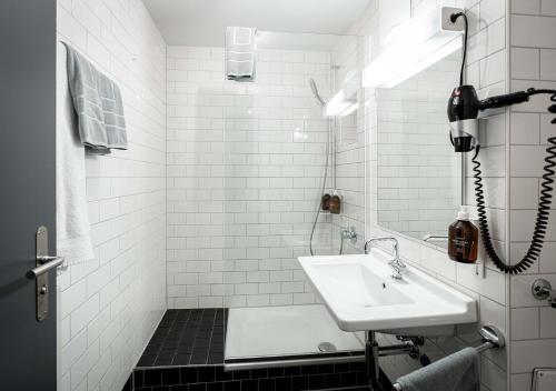 La salle de bains blanche est pourvue d'un lavabo et d'une douche. dans l'établissement Gasthaus zum Guten Glück, à Zurich