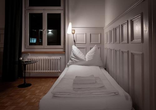 a white bed in a room with a window at Gasthaus zum Guten Glück in Zurich