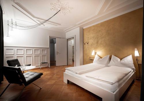 a bedroom with a white bed and a black chair at Gasthaus zum Guten Glück in Zurich