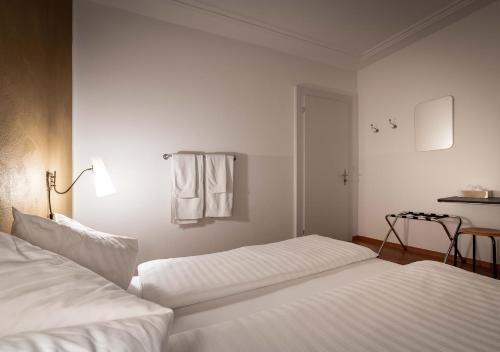 two beds in a hotel room with white sheets at Gasthaus zum Guten Glück in Zurich