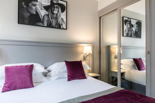 بست وسترن مونكالم في باريس: غرفة نوم مع سرير أبيض كبير مع وسائد أرجوانية