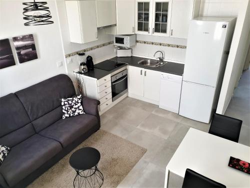 a living room with a couch and a kitchen at Apartament Fora Port in Fornells