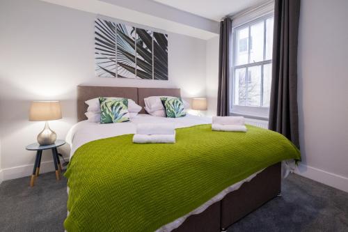 a bedroom with a large bed with a green blanket at Beautiful Central Apartment in Brighton & Hove