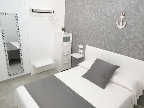 Habitación blanca con cama y espejo en Apartament Fora Port, en Fornells