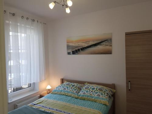 Un dormitorio con una cama y un cuadro en la pared. en Fala Baltyku Apartament, en Ustronie Morskie