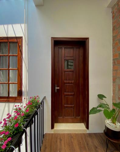 a wooden door on the side of a building with flowers at Okra Hoian in Hoi An
