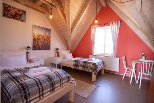 1 dormitorio en el ático con 2 camas y mesa en Tvrz Krassa en Osečná