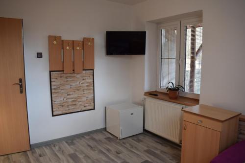 a room with a tv on a white wall with a window at Ubytování u Šveců u Adršpachu in Jívka