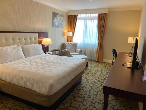 a hotel room with a bed and a chair and a desk at Holiday Inn El Monte - Los Angeles by IHG in El Monte