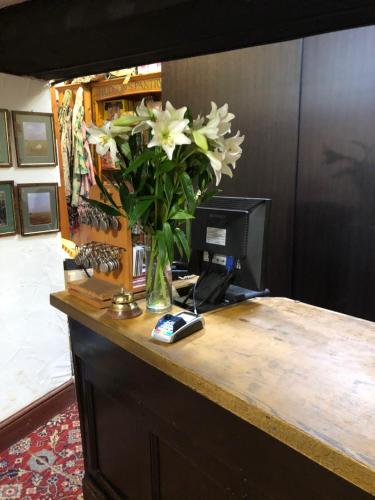 Un escritorio con un jarrón de flores. en The Dog & Partridge Country Inn, en Ashbourne