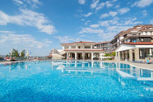 a large swimming pool with blue water in front of buildings at Nevis Resort & Aqua Park - All Inclusive in Sunny Beach