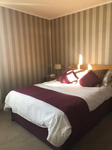 a hotel room with a large bed with pillows at The Dog & Partridge Country Inn in Ashbourne