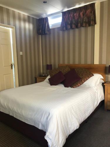 a bedroom with a large bed with white sheets and pillows at The Dog & Partridge Country Inn in Ashbourne