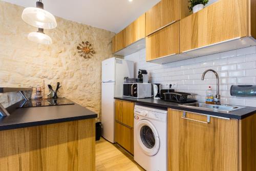 Il comprend une cuisine équipée d'un lave-linge et d'un réfrigérateur blanc. dans l'établissement CMG Réaumur Sébastopol - Tracy 3, à Paris