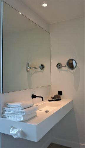 a bathroom with a sink with a mirror and towels at Van der Valk Hotel Tilburg in Tilburg