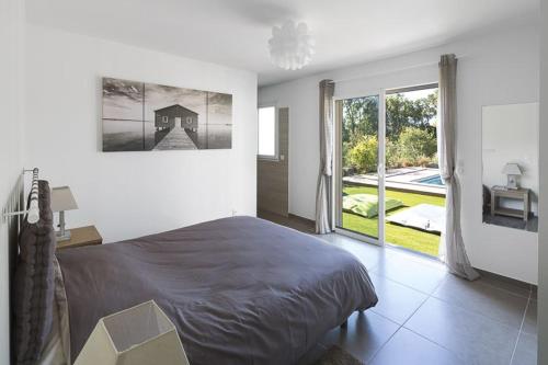 une chambre avec un grand lit et une grande fenêtre dans l'établissement Villa Poggio Rosso - Pool-House & Piscine chauffée, à Sainte-Lucie de Porto-Vecchio