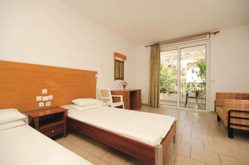 a hotel room with two beds and a balcony at Coliseum Studios & Apartments in Pefki Rhodes