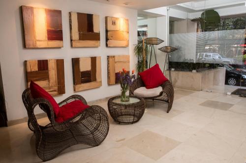 Suites Giorgio في مدينة ميكسيكو: غرفة بها كرسيين وطاولة مع وسائد حمراء
