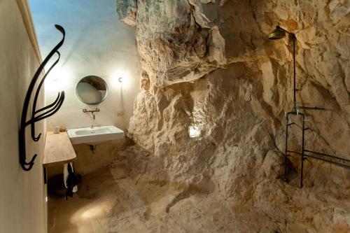 a bathroom with a rock wall with a sink at IL CORVO DI PIETRA in Scicli