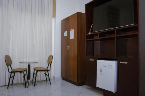a room with a tv and a table and chairs at Pioneiro Hotel in Teixeira de Freitas