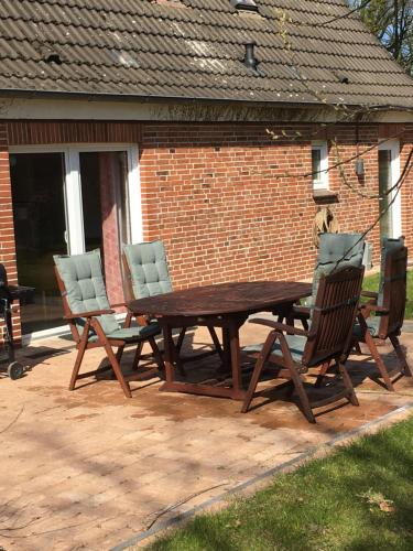 a wooden table and four chairs on a patio at Huck’s Ferienhäuser in Borstel