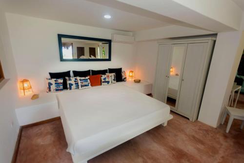 a bedroom with a white bed and a mirror at Villa Ibiscus in Las Galeras