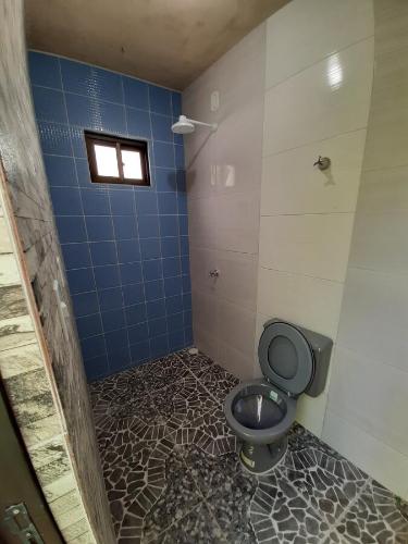 a bathroom with a toilet and a blue tiled wall at Beach House Maragogi in Maragogi
