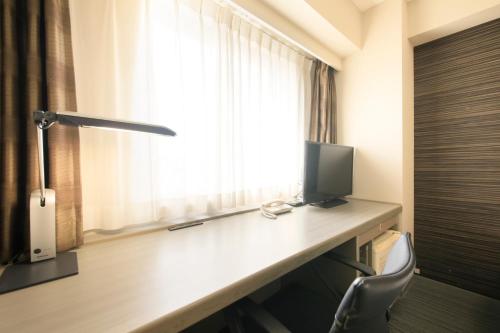 a room with a desk with a television and a window at Daiwa Roynet Hotel Tokyo Osaki in Tokyo