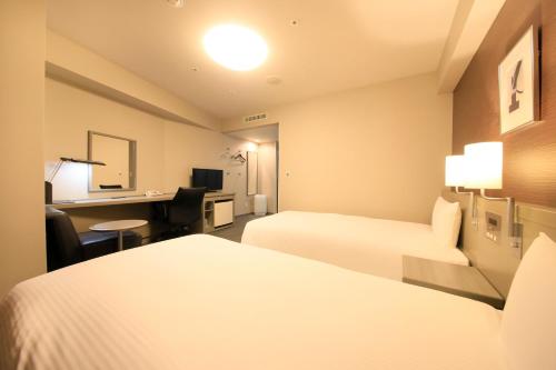 a hotel room with two beds and a desk at Daiwa Roynet Hotel Tokyo Osaki in Tokyo
