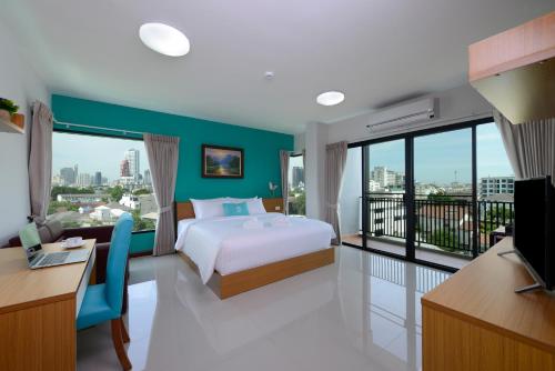 una camera con letto, scrivania e balcone di SiRi Ratchada Bangkok a Bangkok