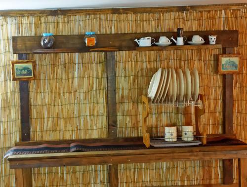 une étagère avec des bols et des tasses sur un mur de paille dans l'établissement Taberna di felisiano, à Torre Canne