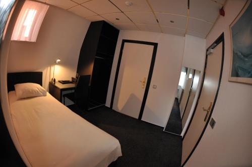 a hotel room with a white bed and a desk at Budget Hotel Le Beau Rivage in Middelburg
