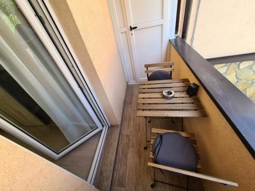 a balcony with a wooden table and a window at Adonis Apartment in Novi Sad