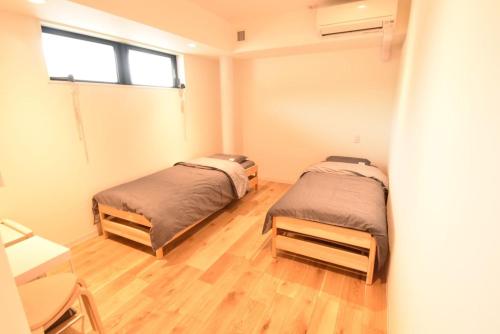 2 Betten in einem Zimmer mit Holzböden und einem Fenster in der Unterkunft Enzo Due in Tamano