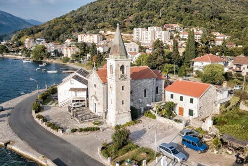 an old church with a steeple on the side of the water at Villa Ruza, Donja Lastva in Tivat