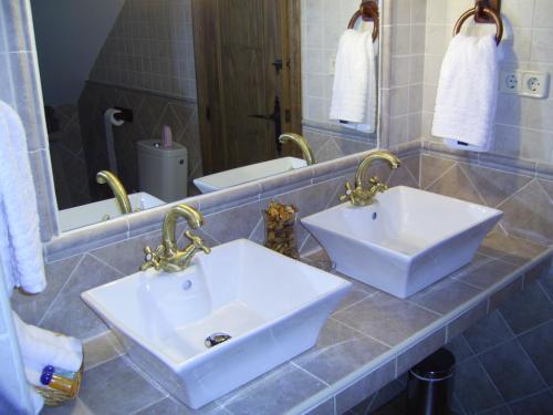 a bathroom with two white sinks and a mirror at La Guarida del Oso in Candeleda