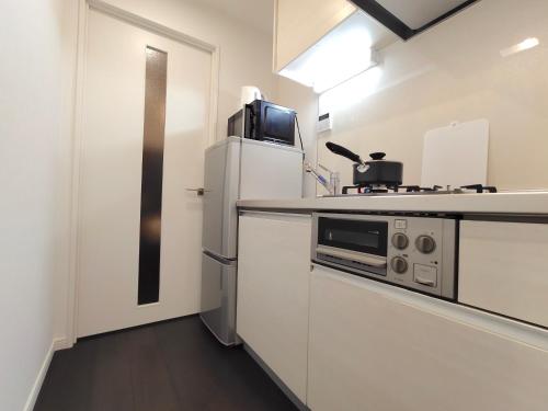 a kitchen with a refrigerator and a microwave at LANG Hotel GINZA 1K with Kitchen 從東銀座站步行3分鐘 帶廚房 हिगाशी गिन्ज़ा स्टेशन से 3 मिनट की पैदल दूरी पर रसोई के साथ in Tokyo
