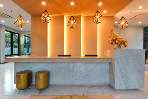 um átrio com um balcão de recepção com bancos de ouro em Sappaya Hotel By Lotus Valley Golf Resort em Chachoengsao