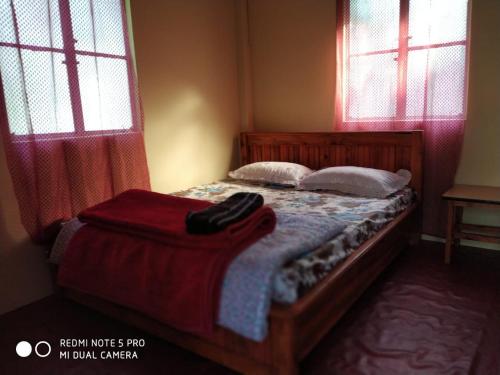 a bedroom with a bed with two pillows and two windows at Vamoose Mingma in Takdāh