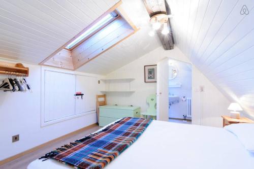 a bedroom with a white bed and a skylight at Appartamento MARMOLADA - CANAZEI in Canazei
