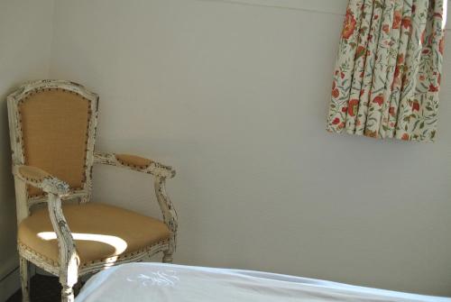 a room with a chair and a window with a curtain at Logis Hôtel Louise de Savoie in Blois