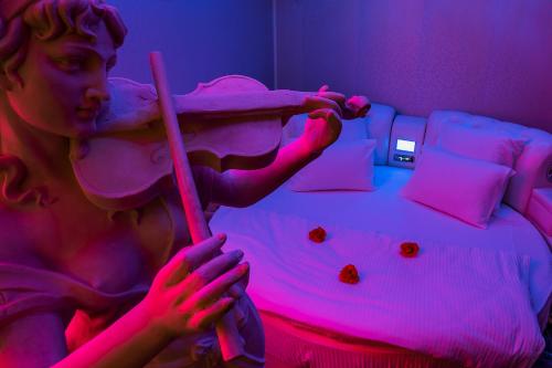 a statue of a woman holding a stick in a bed at Spa Lux Apartmani in Novi Sad