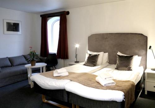 ein Schlafzimmer mit großem Bett und Couch in der Unterkunft Värdshuset Hwitan in Falkenberg